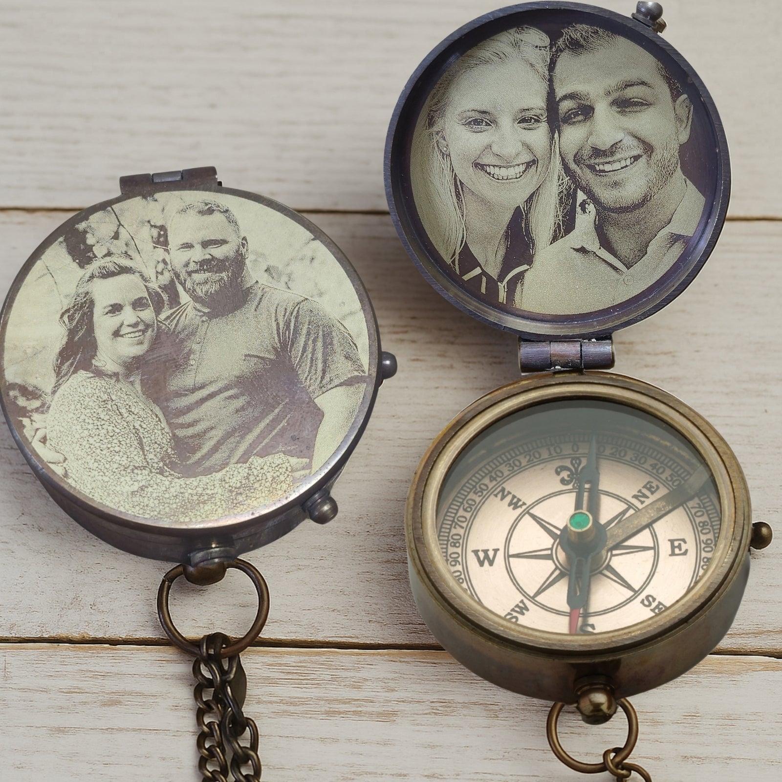 Two vintage-style compasses with engraved images of a couple on a wooden surface.