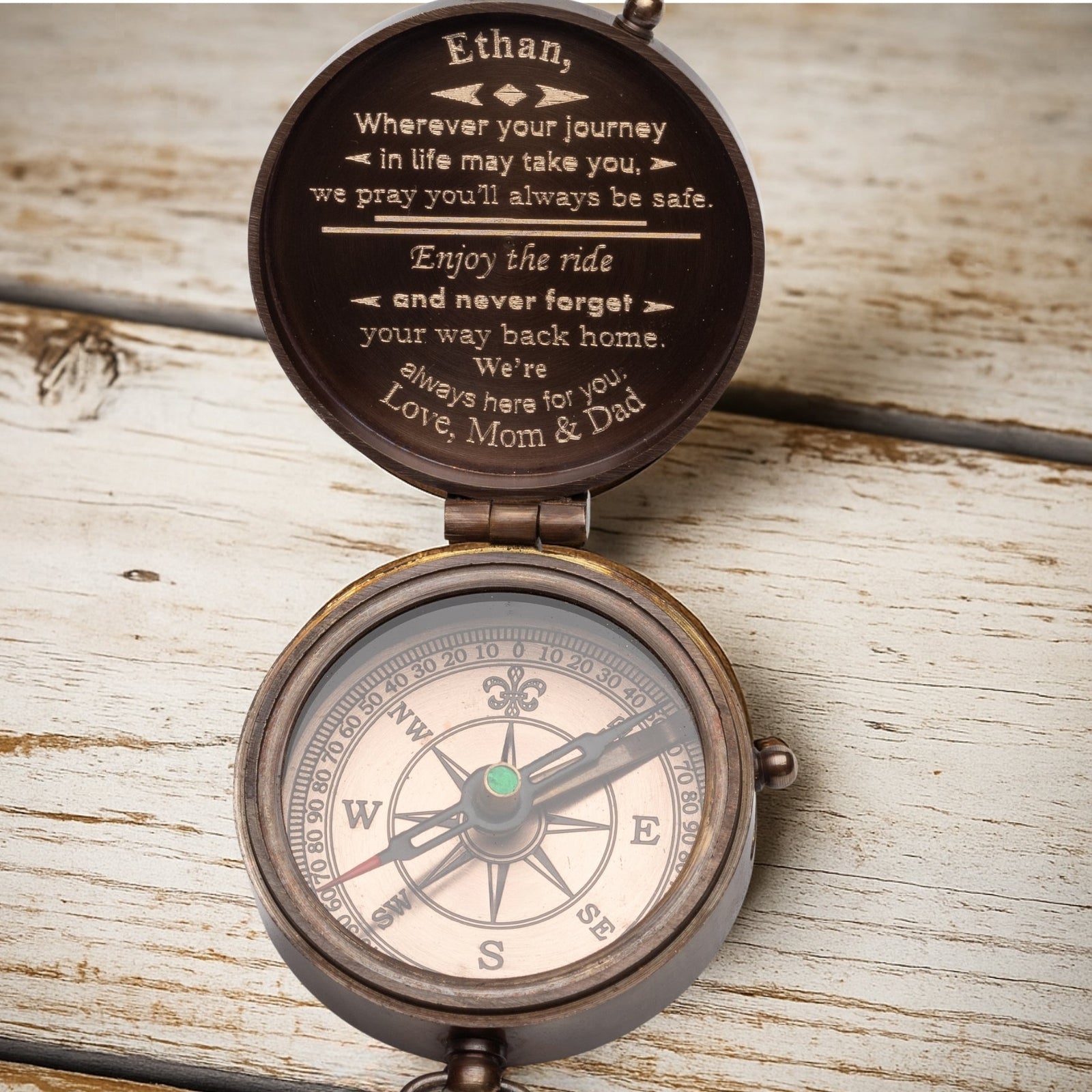 Personalized compass with engraved message on a wooden surface