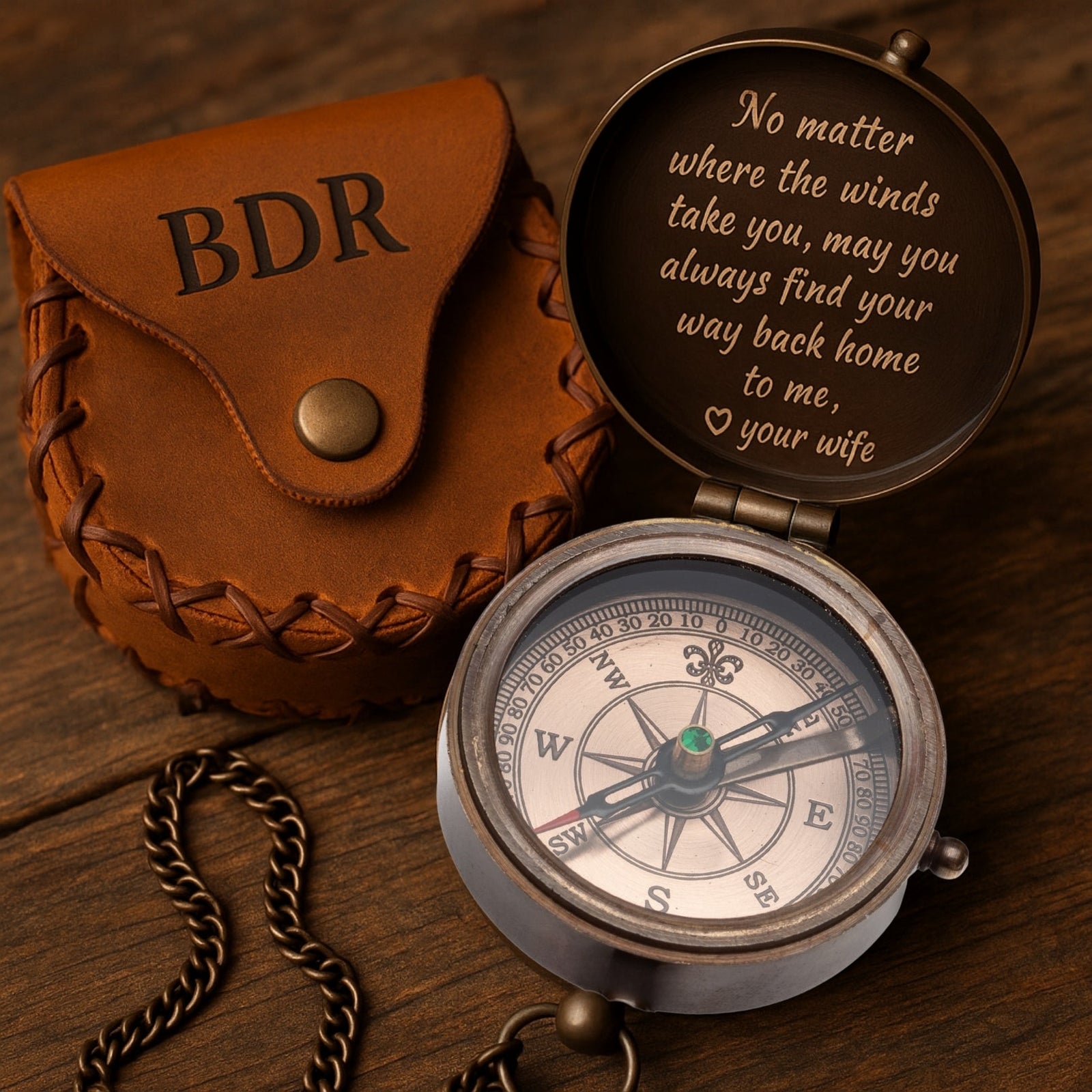 Compass with engraved message and leather case on a wooden surface