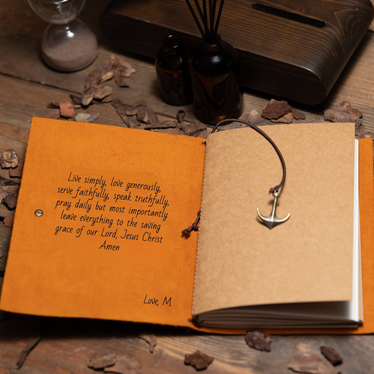 Open book with a quote and anchor pendant on a wooden surface with decorative items.