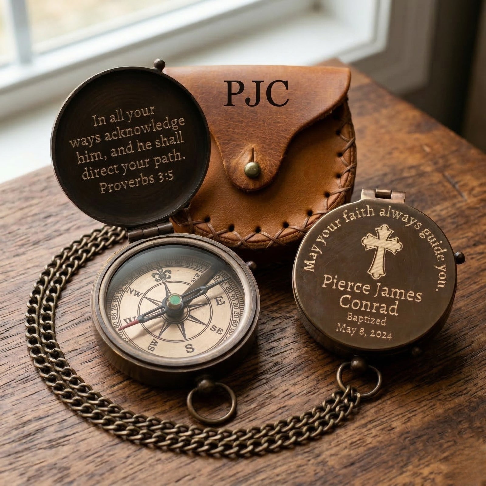 Personalized compass and case on a wooden surface with engraved text.