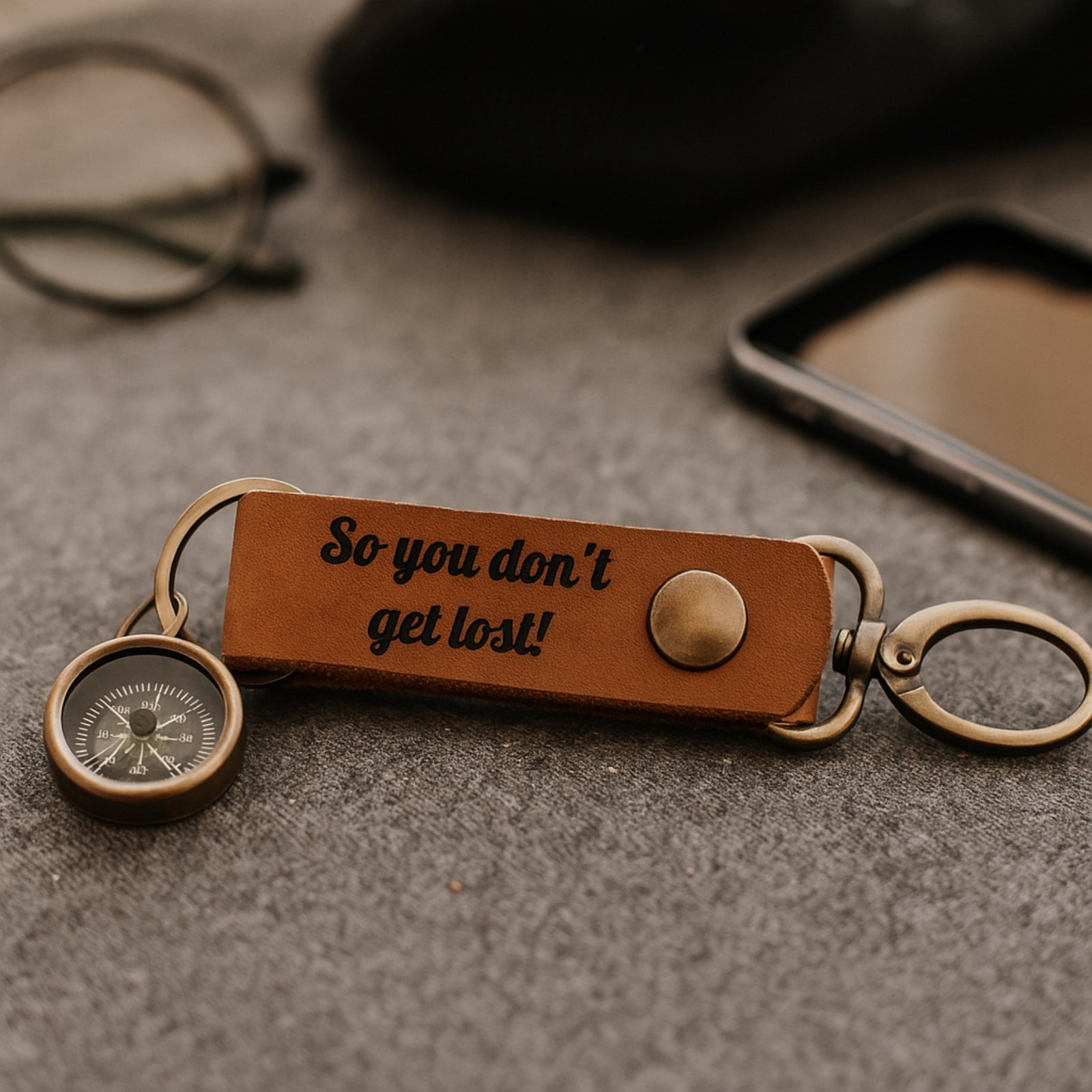 Brown leather keychain with compass and engraved text on a textured surface