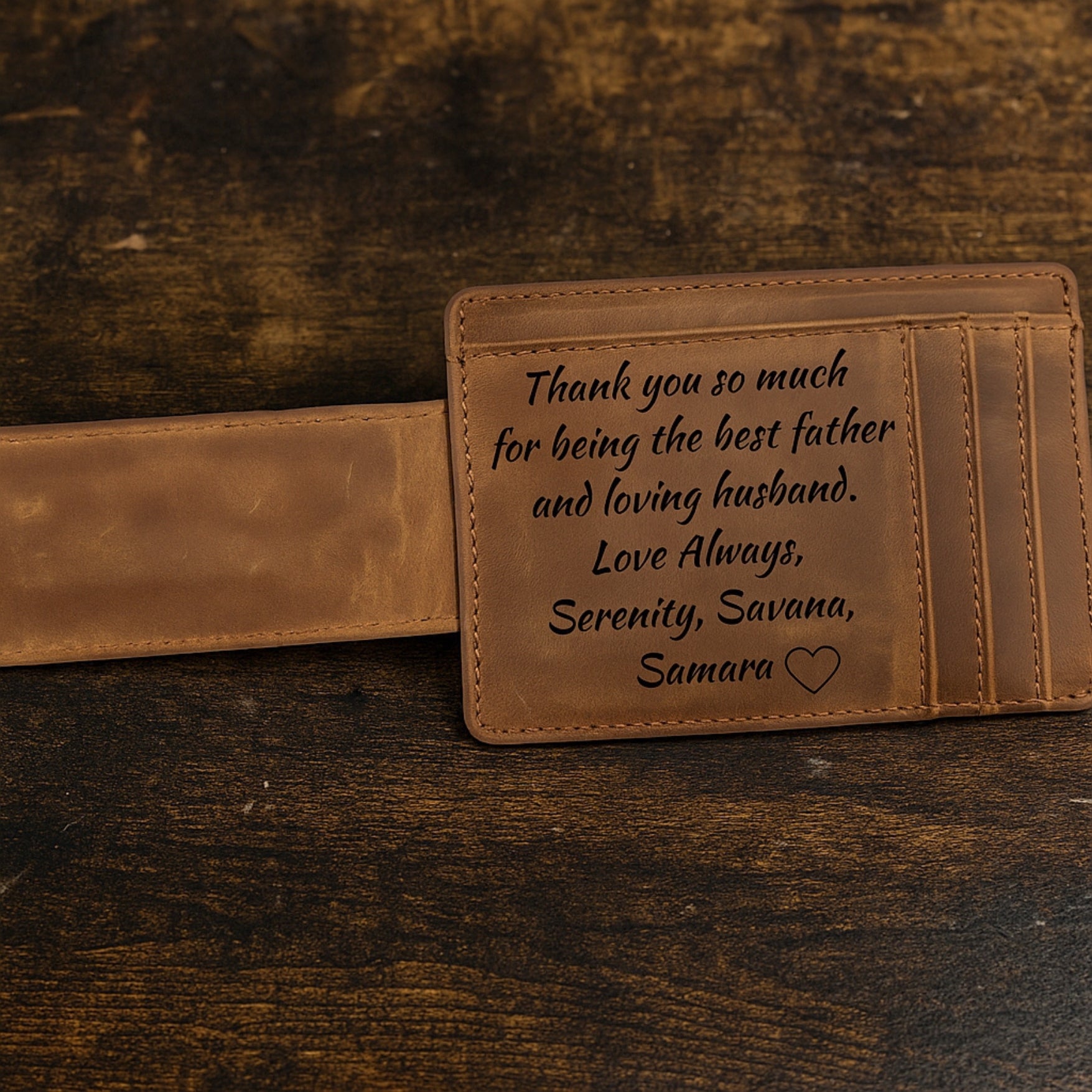 Brown leather wallet with engraved message on a wooden surface