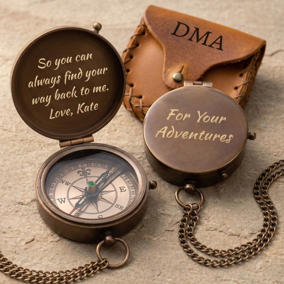 Bronze compass with engraved message and leather case on a textured surface