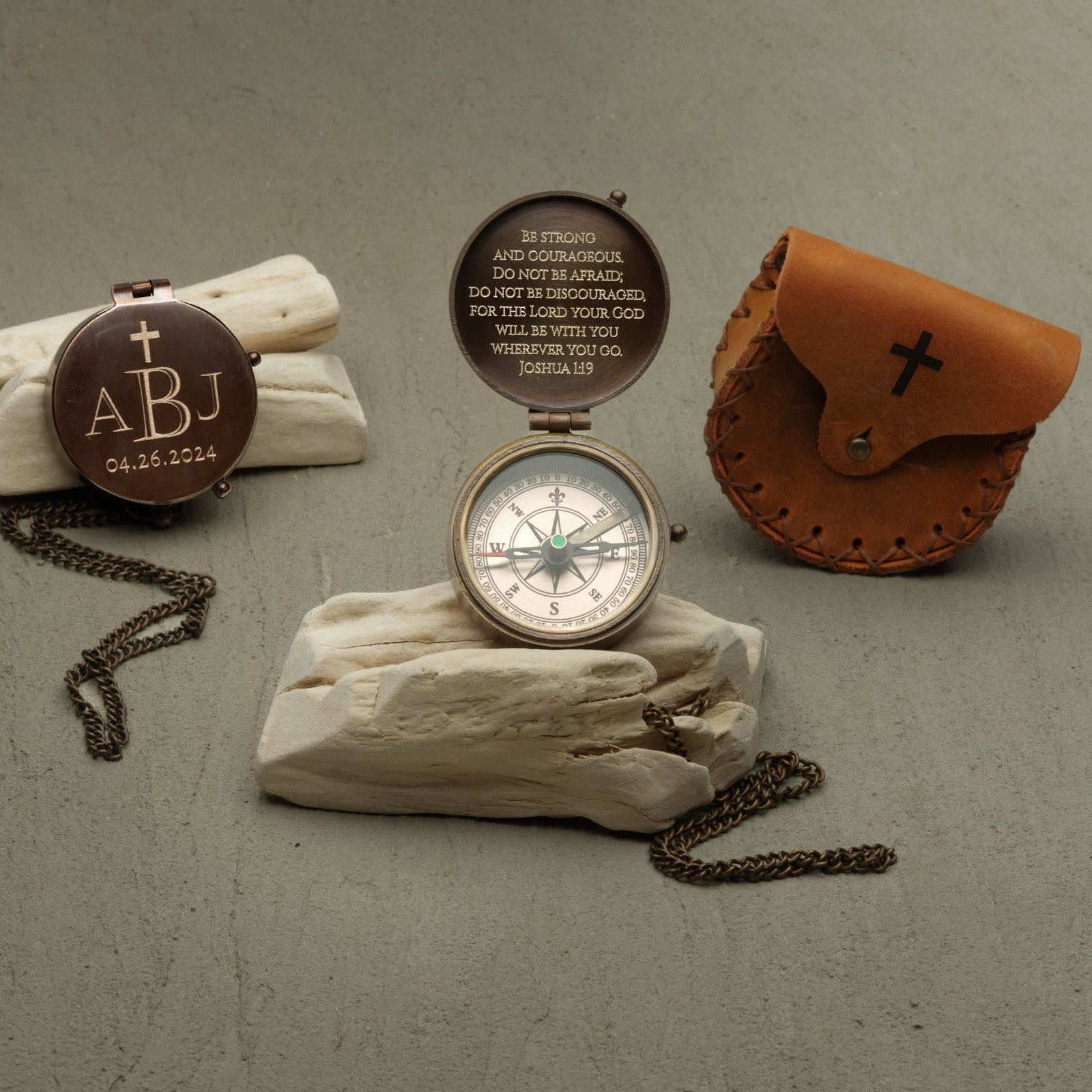 Compass with engraved text and leather case on a textured surface