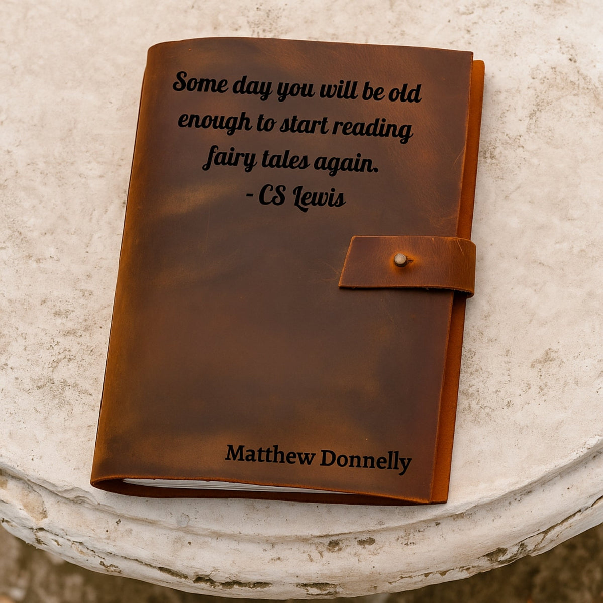 Brown leather notebook with a quote by CS Lewis on a textured surface