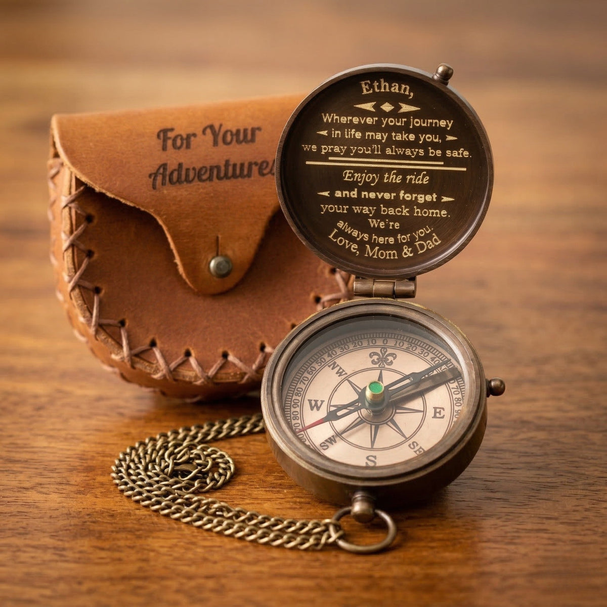 Compass with engraved message in a leather case on a wooden surface